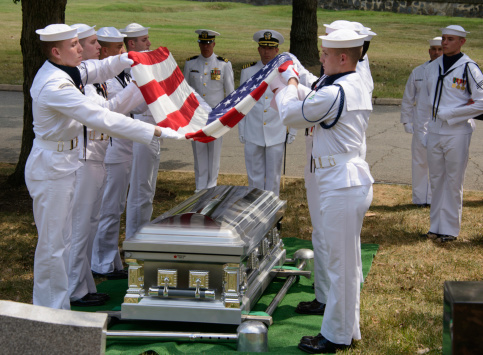 Arlington, VA, USA - August 20, 2013: US Naval Honor Guards fold the US Flag over the casket of a Naval Officer at Arlington National Cemetery