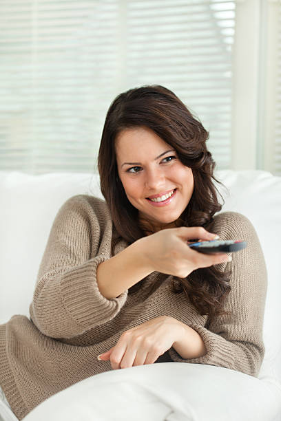istock Smiling young woman holding remote control 477723741