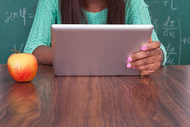 istock Teacher Holding Digital Tablet At School Desk 477726420