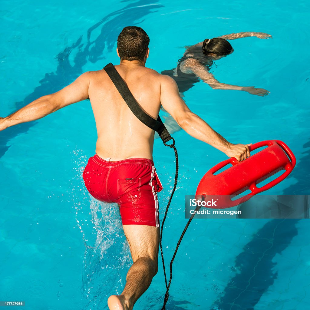 Lifeguard rescue Lifeguard jumping into a swimming pool to rescue drowning victim First Aid Stock Photo