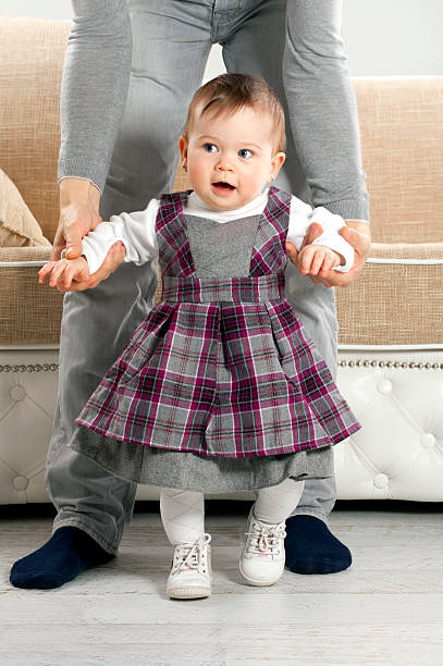 istock Father teaching baby girl to walk 477729873
