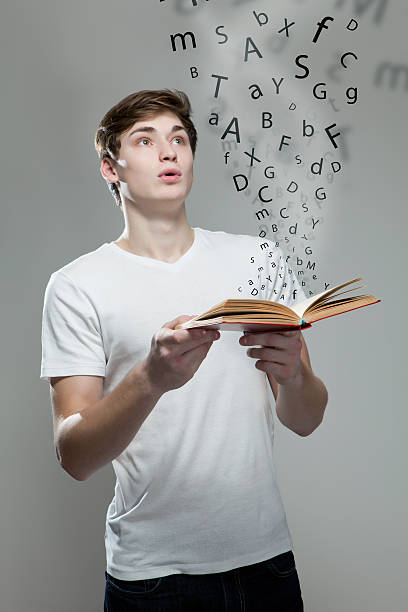 istock Young man holding a book with alphabet letters 477732460