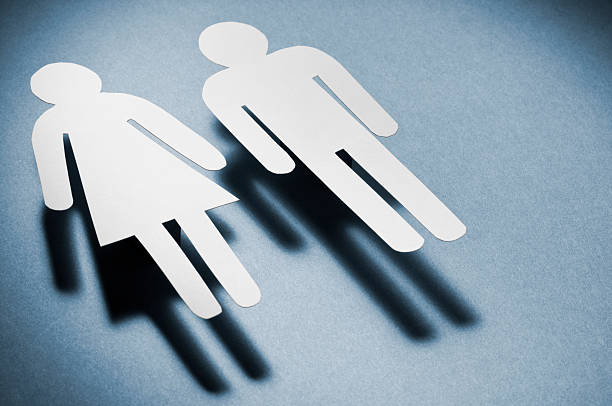 Male and female symbols casting moody shadows ontoo a blue background