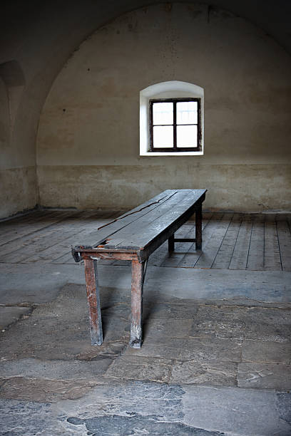 istock Old wooden bench seat in stone floor room 477733785