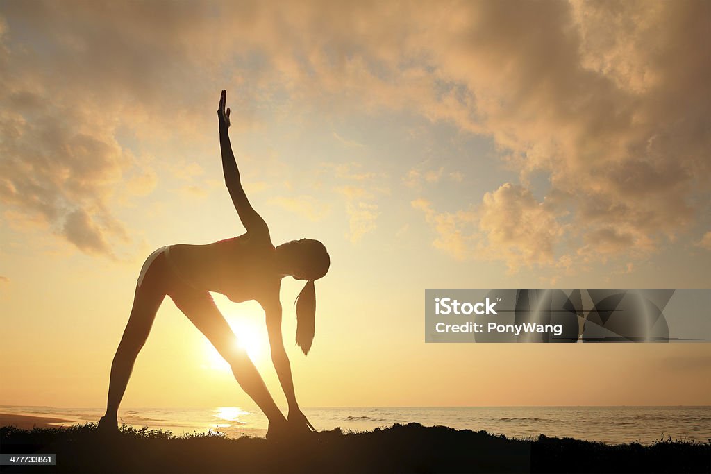 Yoga Young woman silhouette practicing yoga on the sea beach at sunset Adult Stock Photo