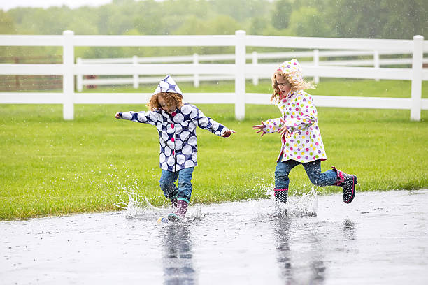 Two Young Girls Running & Splashing In Large Water Puddle