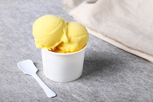 passion fruit sorbet in white cup with a plastic spoon