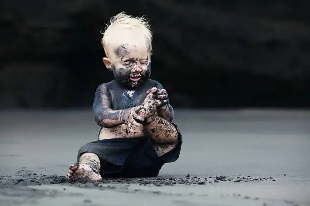 Photo of Portrait of dirty child on the black san beach