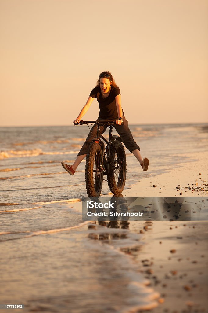 Young woman having a great time riding on the beach. An attractive woman is riding her fatbike on a beach on the Atlantic Ocean. The location is Jekyll Island, one of the barrier islands of Georgia.  Fatbike Stock Photo