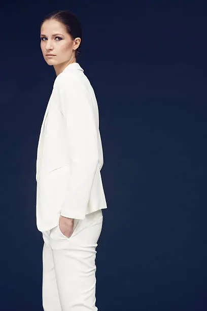 fashionshoot of a model in white jacket against blue background