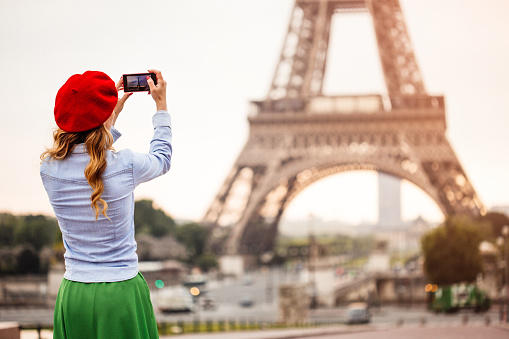 Young woman tourist in red cap looking on the Eiffel tower in Paris