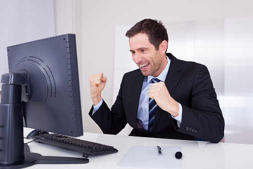 Young businesswoman cheering, screaming at laptop