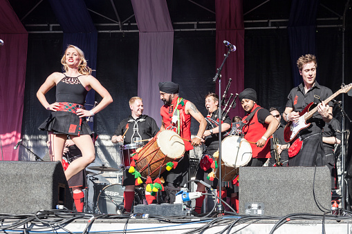Glasgow, Scotland, UK - 14th June, 2015: The Red Hot Chilli Pipers in a one-off collaboration with the Dhol Foundation, performing at Glasgow Mela. One of the Red Hot Chilli Dancers is in the image. The Red Hot Chilli Pipers is a group of Scottish musicians formed in 2002, coining the music genre Bagrock. The Dhol Foundation is a dhol drumming school founded in London in 2001 and a touring dhol musical band.