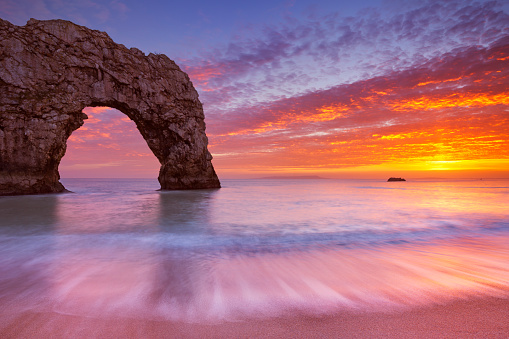 The Durdle Door rock arch on the Dorset Coast of Southern England at sunset.