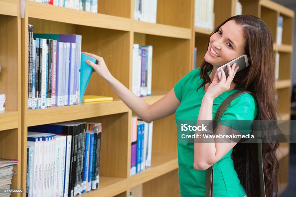 Student using her phone in library Student using her phone in library at the university Book Stock Photo