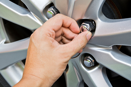 Replacing lug nuts by hand while changing tires on a vehicle.