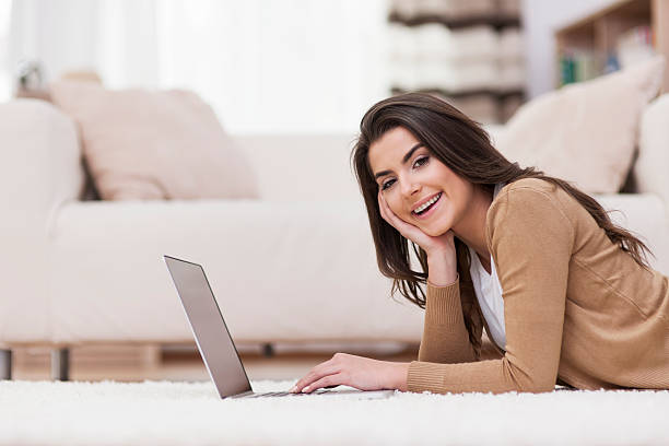 istock Smiling woman relaxing at home with laptop 477758535