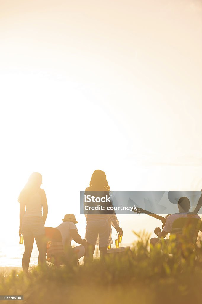 Amici sulla spiaggia al tramonto - Foto stock royalty-free di Abbigliamento casual