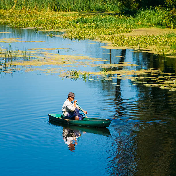 Elderly Man Fishing On River Boat.  Summer