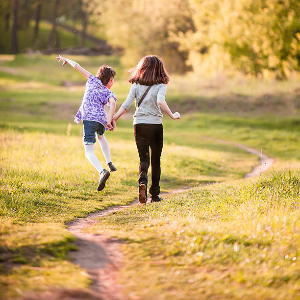 istock Two sisters run on the path in the spring's fielld 477763307