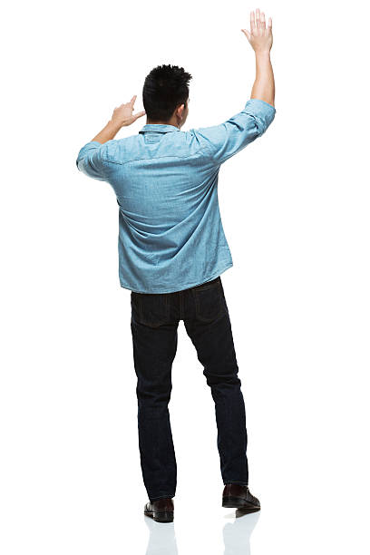 Rear view of man standing with hand raised stock photo