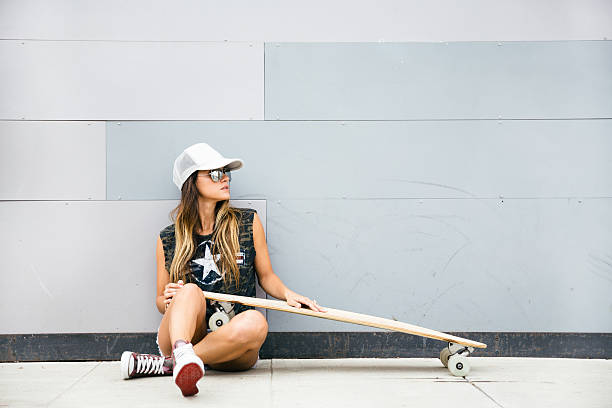 Young girl sitting with her skateboard and smiling.