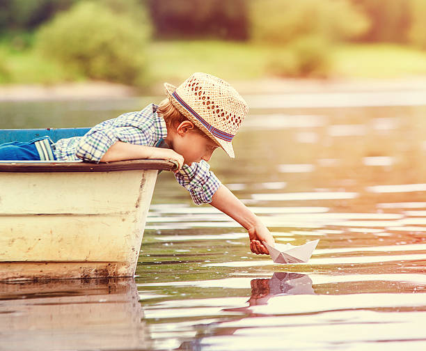 istock Little boy launch paper ship from old boat 477770956