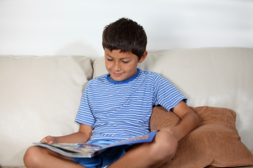 Young boy on the sofa reading a magazine