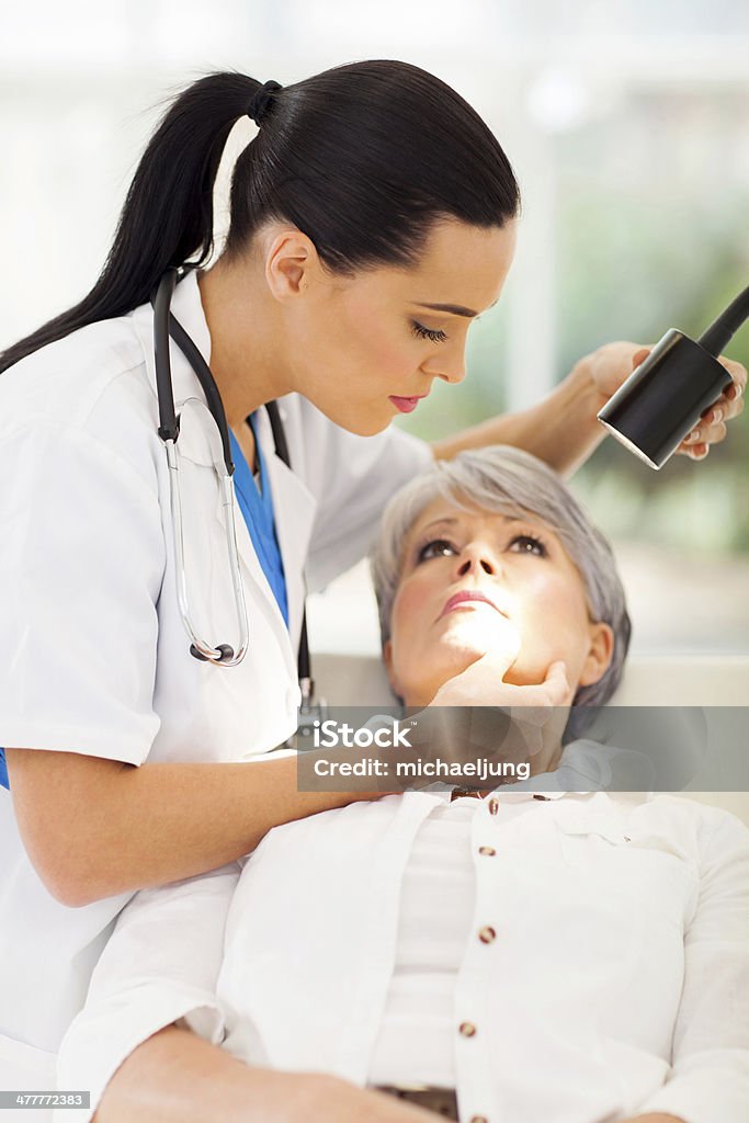dermatologist inspecting middle aged patient's skin beautiful dermatologist inspecting middle aged patient's skin in office Dermatologist Stock Photo