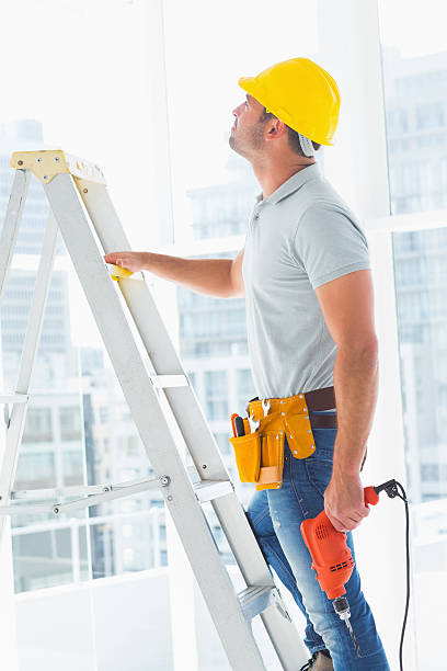 istock Handyman with drill machine climbing ladder in building 477777858