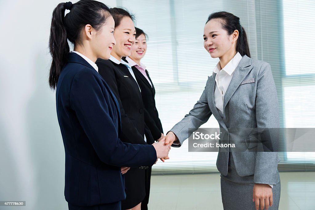 Businesswomen shaking hands Group of business people shaking hands in office room. 2015 Stock Photo