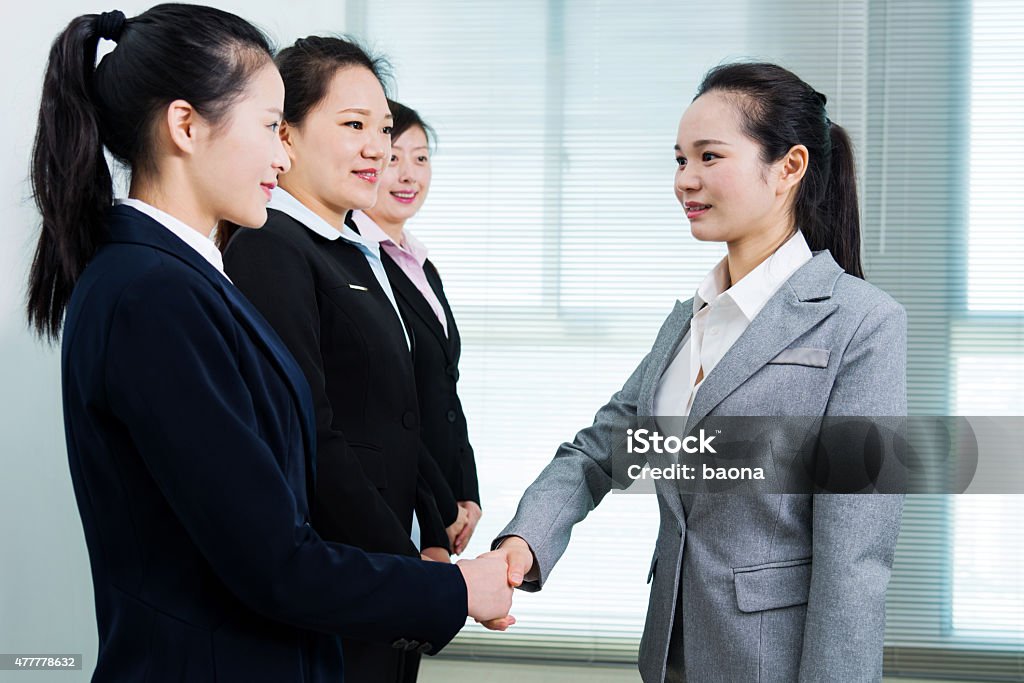 Businesswomen shaking hands Group of business people shaking hands in office room. 2015 Stock Photo