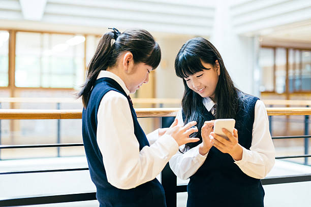 日本の高校の女の子がスマートフォンを使用しての学生の学校 - japanese culture asian ethnicity friendship computer ストックフォトと画像