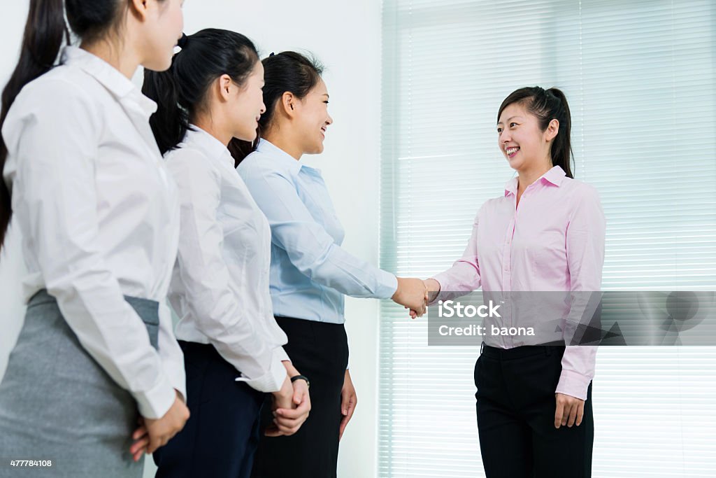 Businesswomen shaking hands Group of business people shaking hands in office room. 2015 Stock Photo