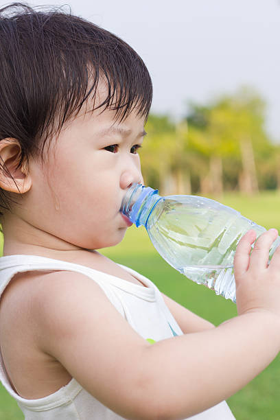 istock Little asian girl  drinking water from plastic bottle 477785472