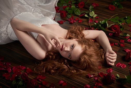 Red-haired woman with a rose in her hands on a light background emotions model portrait close-up. High quality photo