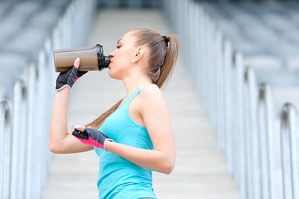 Portrait of healthy fitness girl drinking protein shake Portrait of healthy fitness girl drinking protein shake. Woman drinking sports nutrition beverage while working out blonde female bodybuilders stock pictures, royalty-free photos & images