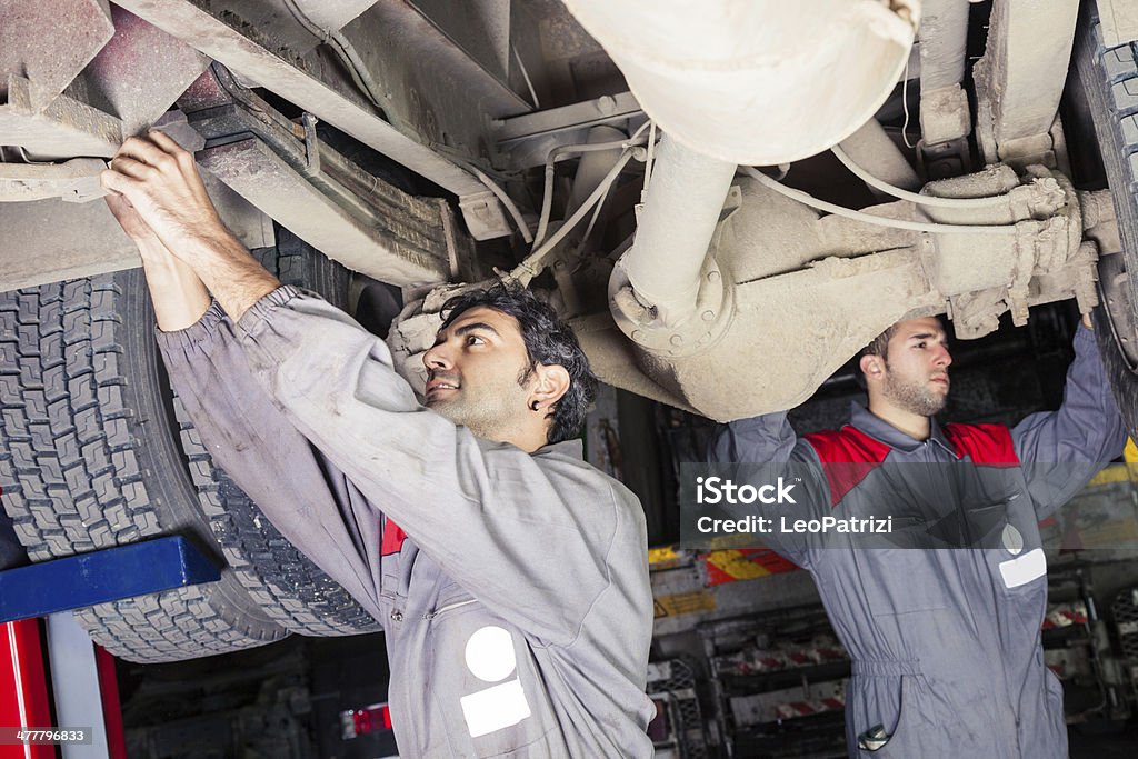 Mechanics working below a truck Mechanics working below a truck. Truck Stock Photo