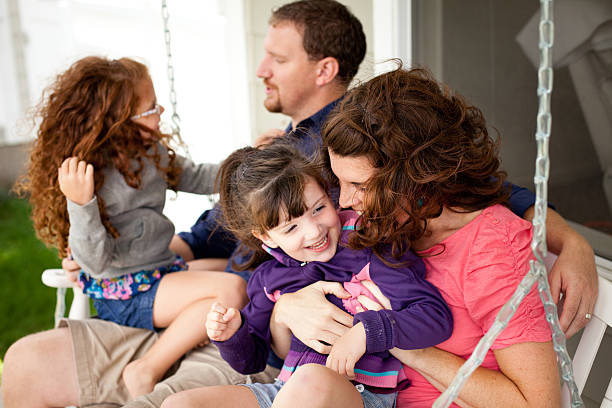 istock Happy Sisters Playing With Mom and Dad on Porch Swing 477797015