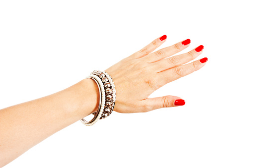 Closeup hands of young woman with red manicure polished nails wearing many silver bangles and pearl bracelets. Isolated on white background