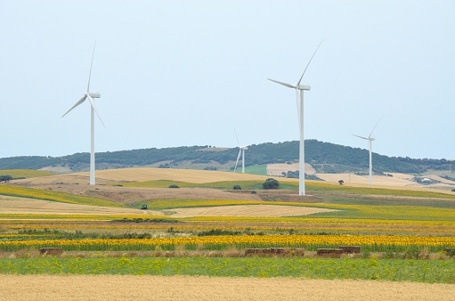 A group of wind turbines on the ridge of a mountain in the distance.