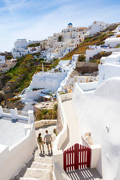 Island walking for two happy young couple walking on background traditional Greek architecture in island Santorini happy couple on vacation in santorini greece stock pictures, royalty-free photos & images