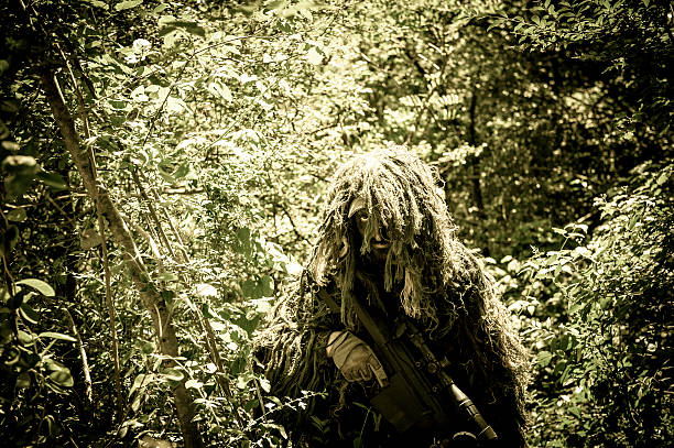 Sniper Soldier Hiding in Bush with Ghillie and Precision Rifle stock photo