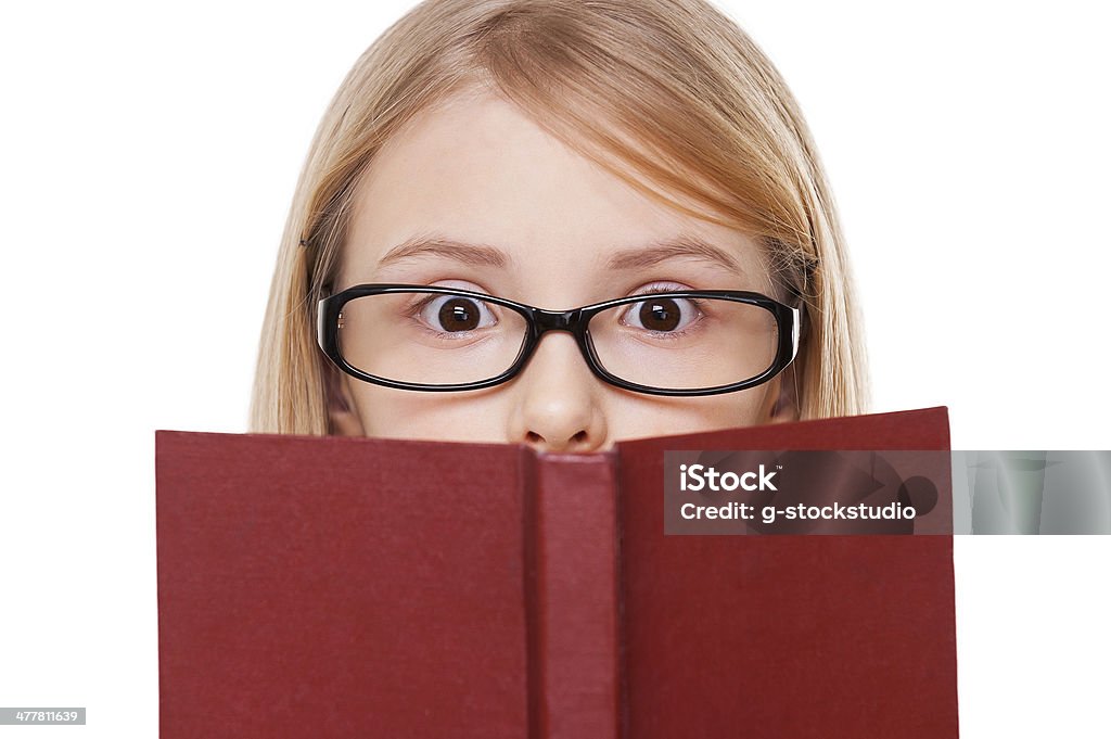 No way! Surprised little girl reading book and keeping mouth open while standing isolated on white Book Stock Photo