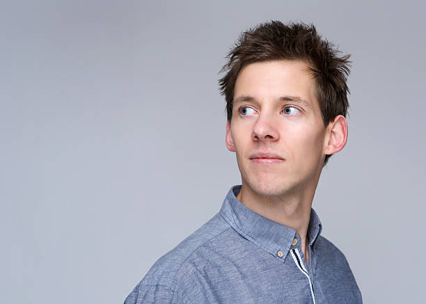 Young man looking away on gray background
