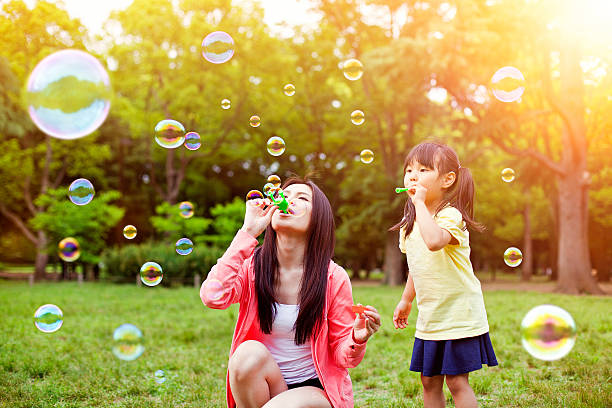 母と娘の楽しみ公園、石鹸の泡 - bubble wand child blowing asian ethnicity ストックフォトと画像