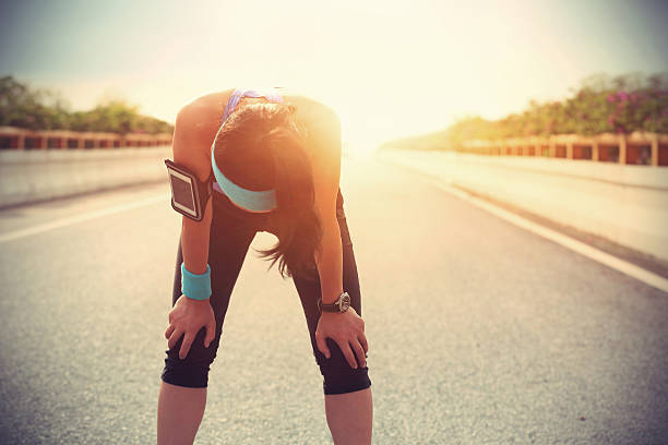 cansado mulher corredor de tomar uma cápsula de repouso após a execução - asian ethnicity jogging female women imagens e fotografias de stock