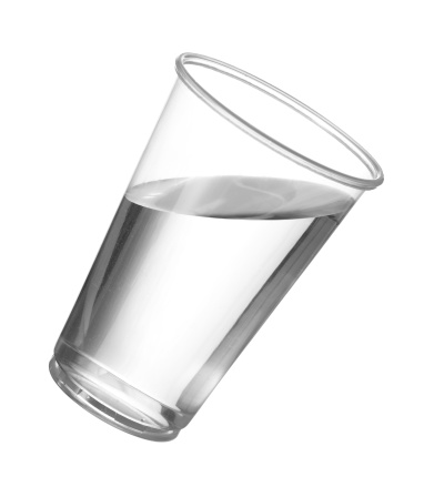 Pure drinking water in disposable cup or glass with water starting to spill over edge of pint glass