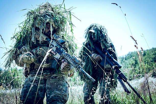 Sniper and Spotter Soldiers Hiding with Ghillie Suit Walking Alert stock photo