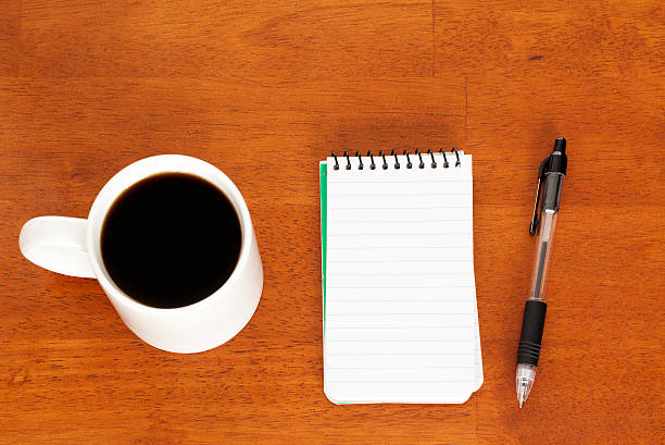 Blank Notebook, Inkpen, Cup of Coffee on Wood Background Blank notebook page with an inkpen beside a full cup of coffee. Shot in studio with Canon 5D Mark II DSLR camera from directly above. inkpen stock pictures, royalty-free photos & images